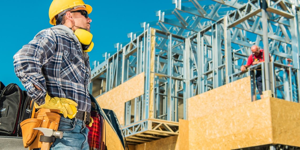 Skeleton Steel House Building. Construction Business Concept. Caucasian Worker in Yellow Hard Hat Taking Short Break During Working Hours.