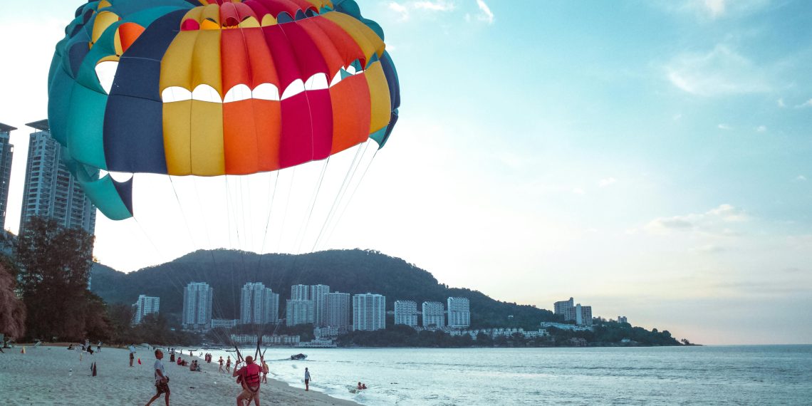 Photo by Donald Tong: https://www.pexels.com/photo/man-riding-parachute-on-the-beach-65310/