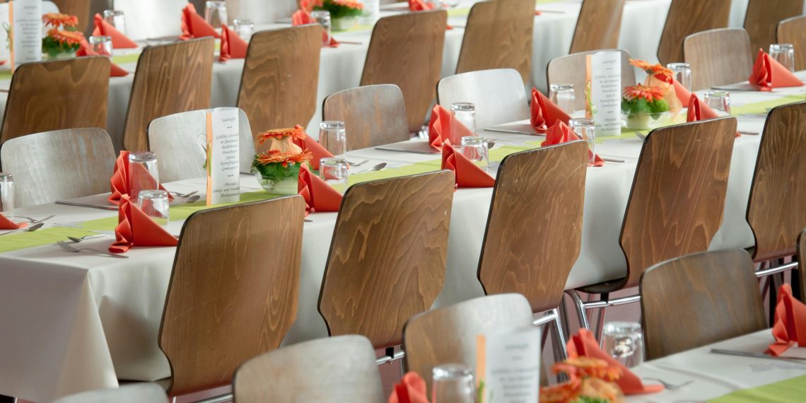 Photo by Pixabay: https://www.pexels.com/photo/long-tables-with-white-cloths-and-brown-chairs-formal-setting-50675/